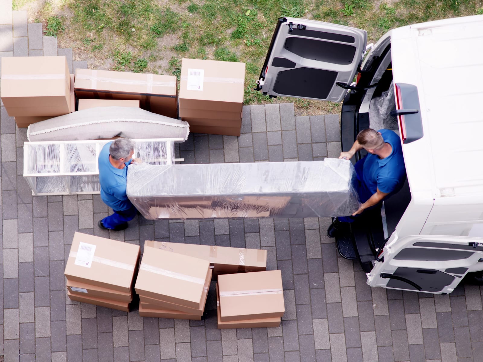 Two movers wrapping furniture beside a loading van
